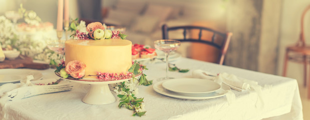 Wedding cake with flowers, boho style table setting toned. Holiday cake on table