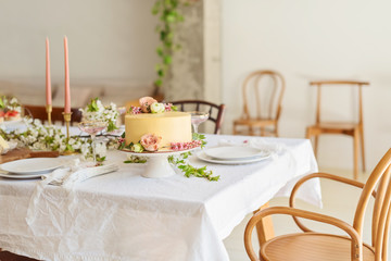 Festive wedding table with cake, champagne, candles and snacks