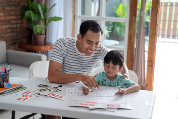 portrait of asian toddler studying with her father at home.