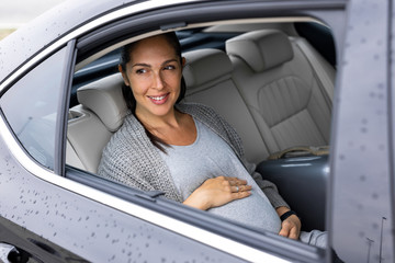 Beautiful young pregnant woman is driving in the car 