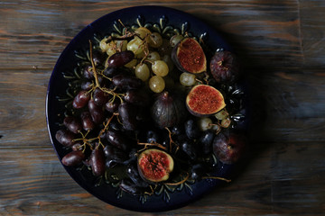 Freshly picked autumn fruits. Black and white grapes and figs on dark wooden table