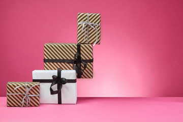 Different sizes, colorful, striped and plain paper gift boxes tied with ribbons and bows on a pink...