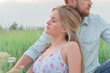 Obraz premium Love story of the beautiful bearded man and woman on green summer meadow