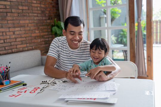 portrait of asian toddler studying with her father at home.