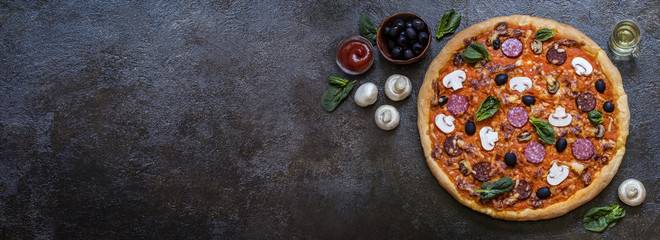 pizza with mushrooms, olives, spinach and sausage and greens on a dark background