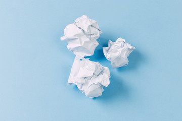 Crumpled paper balls, waste and recycling concept on blue background