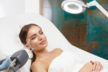 Cosmetology. Closeup Of Female Face having facial treatment in beauty salon. Cosmetic procedures in...