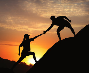 Hiker helping friend outdoors at sunset. Help and support concept