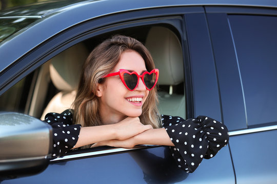 Young beautiful woman wearing heart shaped glasses in car