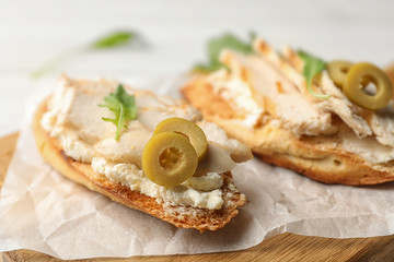 Board with delicious chicken bruschettas on table, closeup