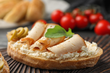 Board with delicious chicken bruschetta on table, closeup