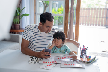 father and daughter studying together using smartphone at home