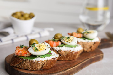 Cutting board of delicious bruschettas with shrimps on grey table