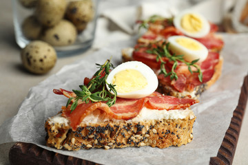 Cutting board of delicious bruschettas with prosciutto on table