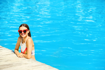 Beautiful young woman in swimming pool on sunny day