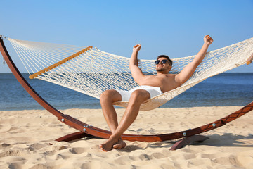 Young man relaxing in hammock on beach