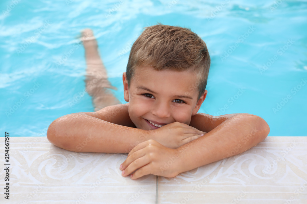 Poster cute little boy in outdoor swimming pool