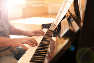 Man playing piano indoors, closeup. Music lesson