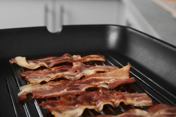 Slices of tasty fried bacon in grill pan indoors