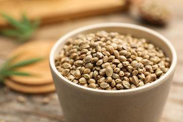 Organic hemp seeds in bowl on table, closeup