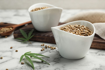 Organic hemp seeds in bowl on marble table
