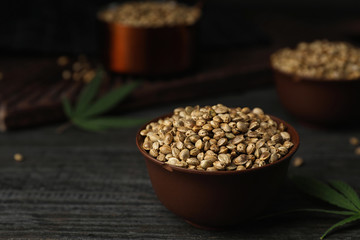 Organic hemp seeds in bowl on black wooden table