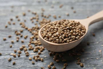 Organic hemp seeds in spoon on grey wooden table