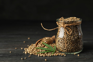 Organic hemp seeds and leaf on black wooden table