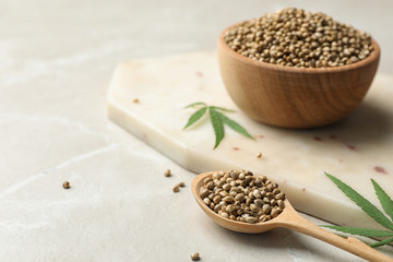 Organic hemp seeds and leaves on light marble table