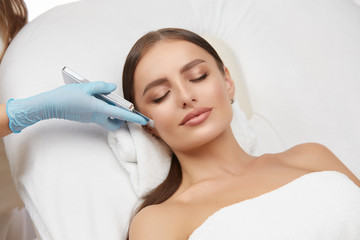 Cosmetology. Closeup Of Female Face having facial treatment in beauty salon. Cosmetic procedures in...