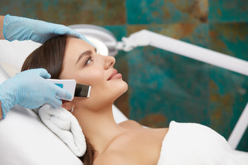 Cosmetology. Closeup Of Female Face having facial treatment in beauty salon. Cosmetic procedures in...