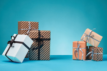 Different sizes, colorful, striped and plain paper gift boxes tied with ribbons and bows on a blue...