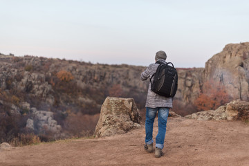 Back view of old gray-haired tourist with a beard on the background of the gorge and stones