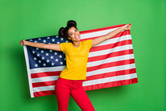 Photo of amazing dark skin lady celebrating independence usa day holding big national flag wear casual yellow t-shirt red pants isolated green background