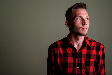 Young man wearing red checkered shirt against colored background