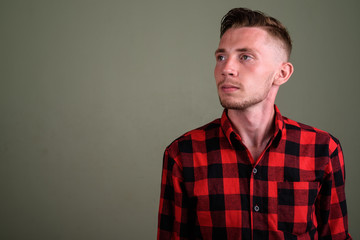 Young man wearing red checkered shirt against colored background