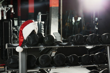Santa hat on stand with dumbbells in modern gym