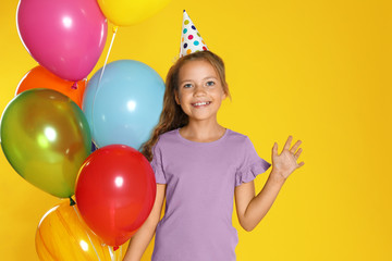 Fototapeta na wymiar Happy girl with balloons on yellow background. Birthday celebration