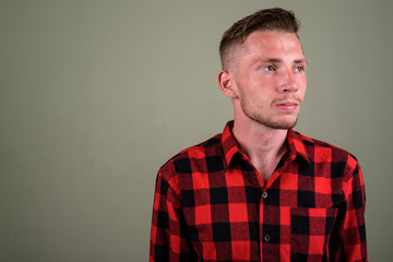 Fototapeta premium Young man wearing red checkered shirt against colored background