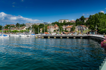 View of the pier, buildings and port in the city of Thonon les Bains on Lake Geneva in the background the blue sky.