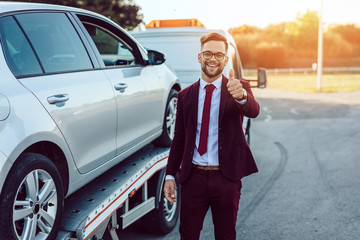 Elegant middle age business man is happy and satisfied with fast towing service for help on the...