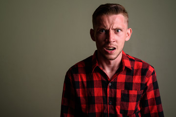 Obraz premium Young man wearing red checkered shirt against colored background