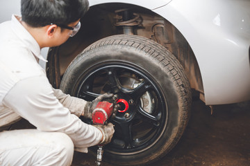 Mechanician changing car wheel in auto repair shop