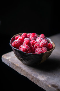 Close up Frozen Raspberry in the bolw on dark background
