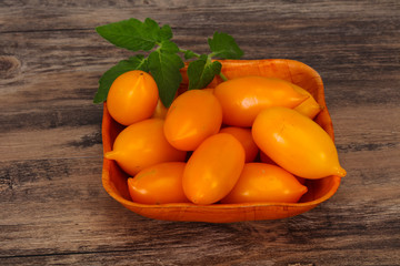 Yellow tomato heap in the wooden bowl