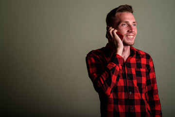 Young man wearing red checkered shirt against colored background