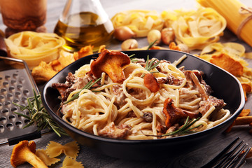pasta with organic chanterelles. portion of spaghetti pasta with fried chanterelles in a creamy garlic sauce with cheese on a table