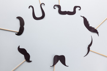 Accessories in form of black moustache on sticks on grey background with place for text. Concept...