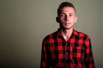 Young man wearing red checkered shirt against colored background
