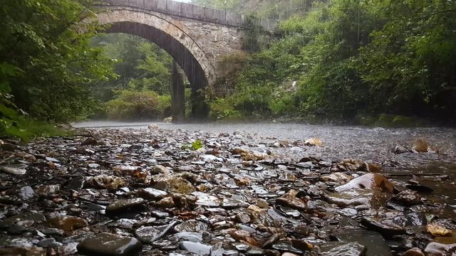 Old Roman Stone Bridge Over Small River Under Heavy Rainfall